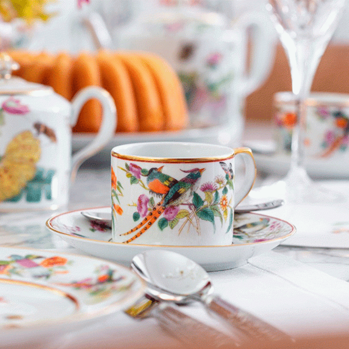Um jogo de chá com um bule branco e xícaras com pinheiros.